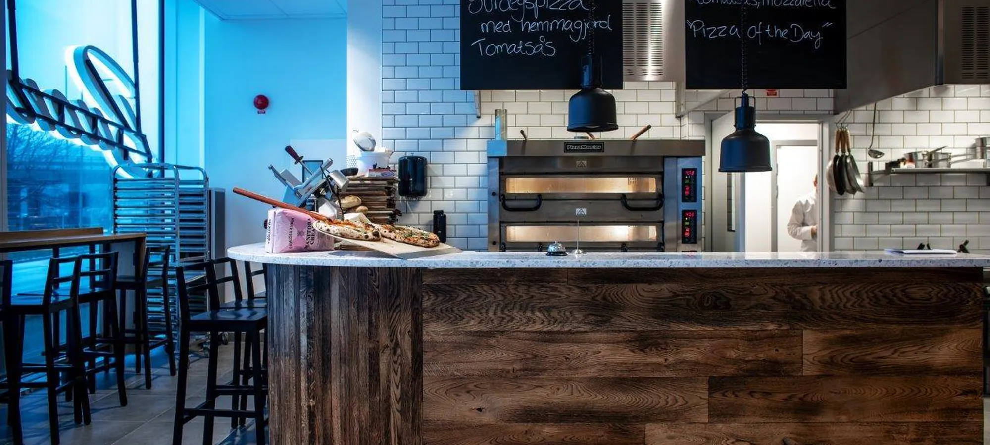 Pizzadisken med stenugnen, nybakad pizza på brädan och kritatavlorna Pizza och Margherita