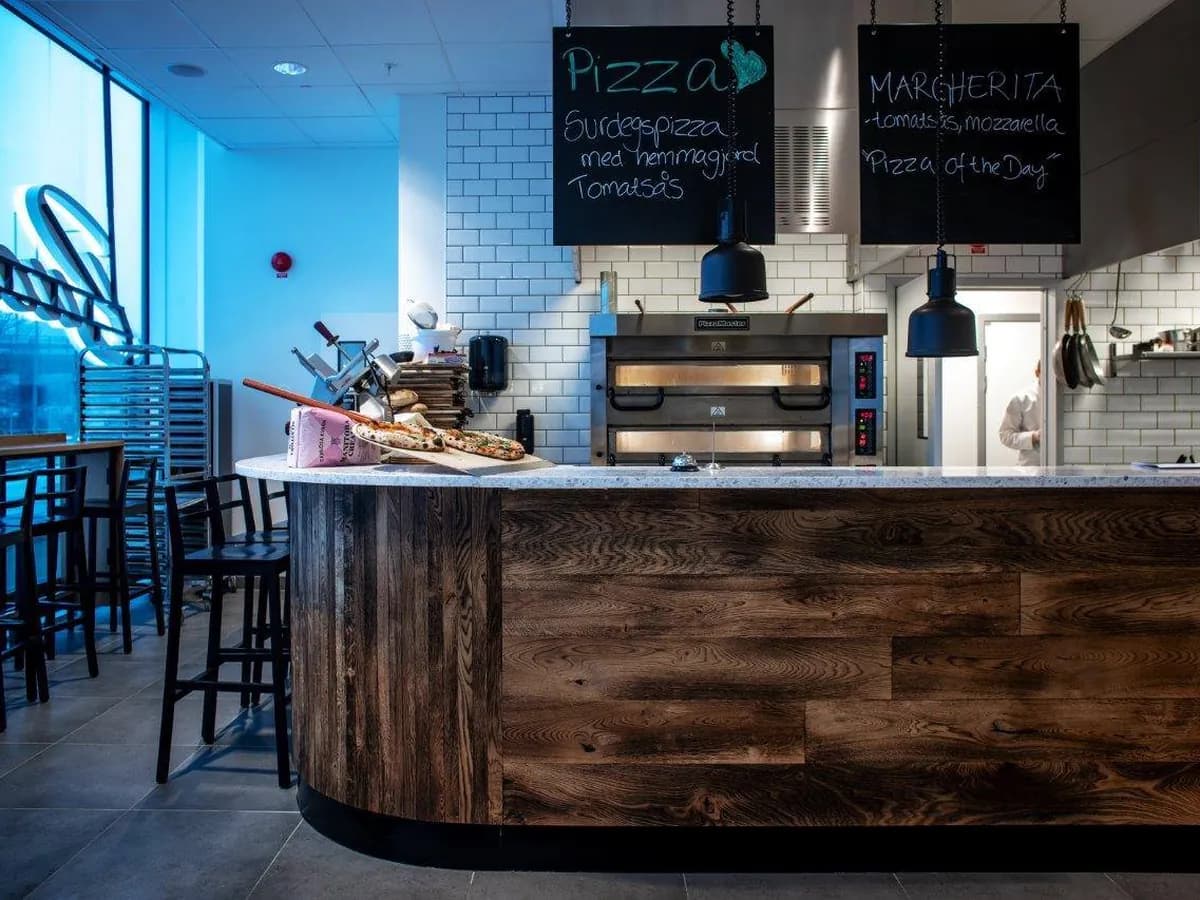 Pizzadisken med stenugnen, nybakad pizza på brädan och kritatavlorna Pizza och Margherita