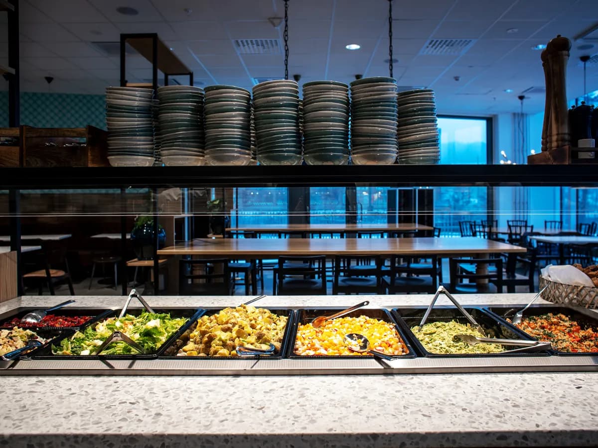 Färska sallader och varmrätter i serveringsbrickor vid lunchbuffén