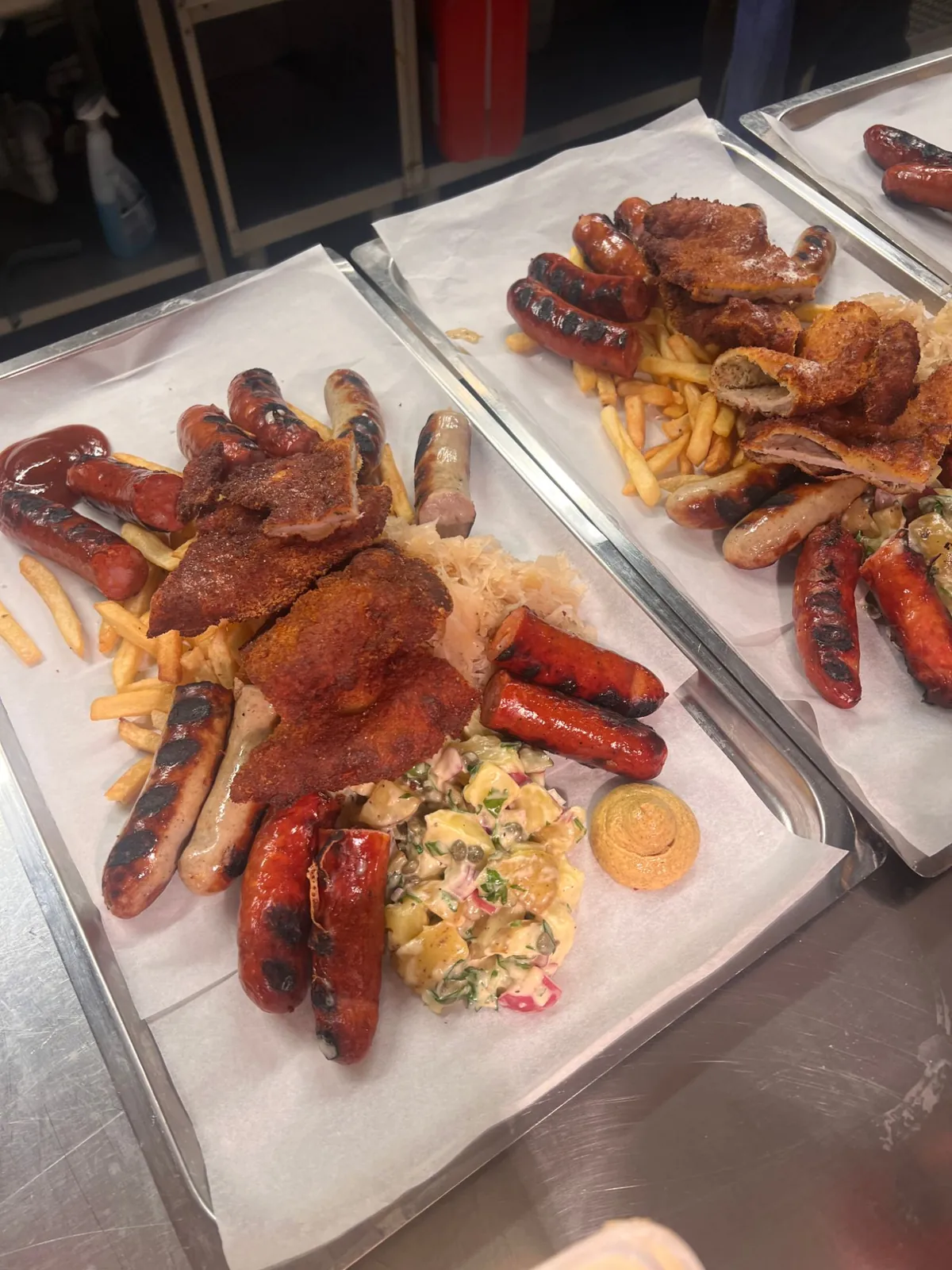 Bricka med grillad korv, schnitzel, pommes frites, surkål, potatissallad och senap